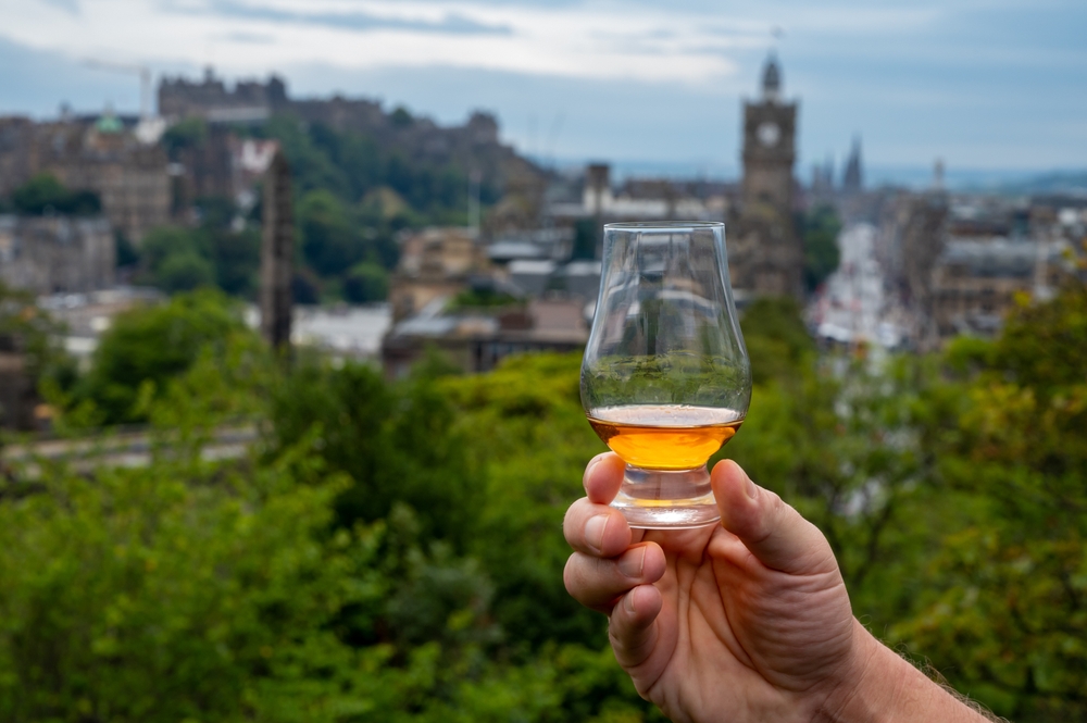 Hand,Holding,Glass,Of,Single,Malt,Scotch,Whisky,And,View
